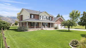 View of front of house with a large porch, a front lawn, concrete driveway, brick siding, and a garage