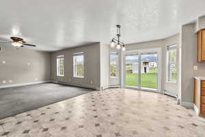 Unfurnished living room featuring a textured ceiling, a baseboard radiator, light colored carpet, a chandelier, and ceiling fan
