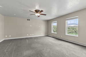 Spare room featuring a baseboard heating unit, light carpet, and ceiling fan
