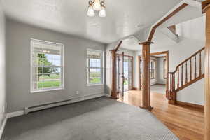 Foyer entrance featuring decorative columns, a baseboard heating unit, stairs, light wood finished floors, and a textured ceiling