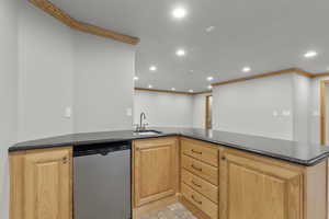 Kitchen featuring recessed lighting, stainless steel dishwasher, crown molding, dark stone countertops, and a peninsula