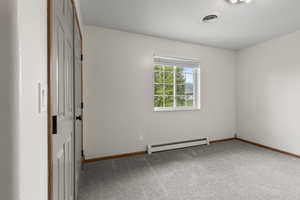 Unfurnished room featuring baseboard heating and light colored carpet