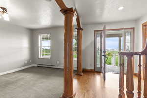 Entrance foyer featuring ornate columns, light wood-style floors, and a textured ceiling