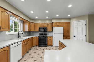 Kitchen with white appliances, recessed lighting, brown cabinets, and light countertops