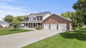 View of front of home with a porch, an attached garage, concrete driveway, and brick siding
