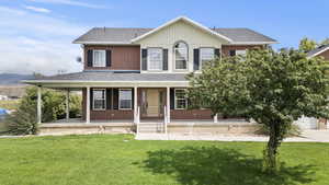 View of front facade featuring a shingled roof, covered porch, a front lawn, and brick siding