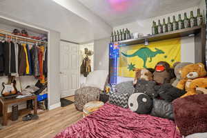 Bedroom with a textured ceiling, wood finished floors, and a closet