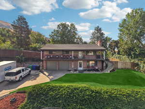 View of front of property featuring concrete driveway, a chimney, brick siding, a garage, and stairs