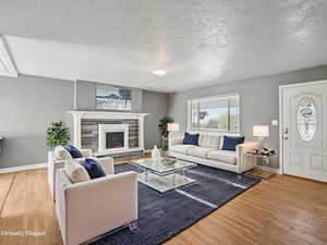 Living area featuring light wood-style floors, a textured ceiling, and a tile fireplace