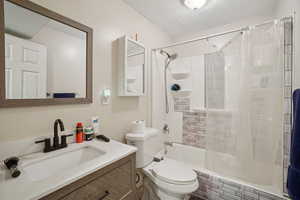 Full bath featuring shower / bath combo, vanity, and a textured ceiling