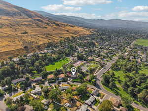 Aerial view of property and surrounding area featuring nearby suburban area and a mountain backdrop