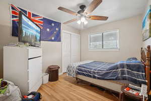 Bedroom with light wood-type flooring, ceiling fan, and a closet