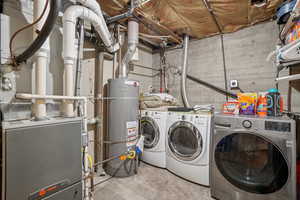 Laundry room with strapped water heater, heating unit, and washing machine and dryer