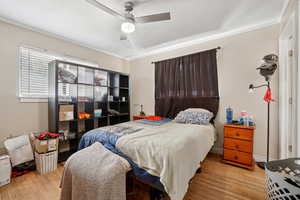 Bedroom featuring wood finished floors, ceiling fan, and ornamental molding