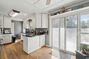 Kitchen featuring a peninsula, white cabinetry, light wood finished floors, ceiling fan, and freestanding refrigerator
