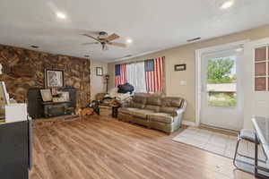 Living area with plenty of natural light, light wood-type flooring, recessed lighting, ceiling fan, and a textured ceiling