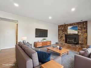 Living room with wood finished floors, recessed lighting, and a wood stove