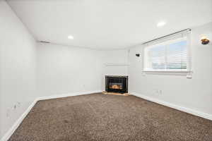 Unfurnished living room with carpet floors, a fireplace with flush hearth, and recessed lighting