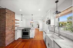 Kitchen with white cabinetry, decorative light fixtures, dark wood-type flooring, recessed lighting, and stainless steel appliances