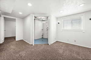 Unfurnished bedroom with carpet floors, a textured ceiling, recessed lighting, and ensuite bath