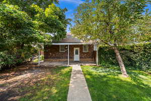 View of front of house featuring a porch, a front lawn, and brick siding