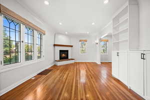Unfurnished living room with recessed lighting, light wood-style floors, arched walkways, and a glass covered fireplace