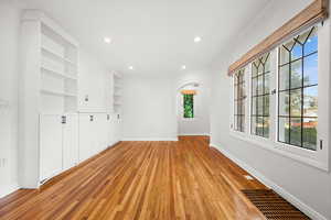 Unfurnished room featuring arched walkways, light wood finished floors, recessed lighting, and built in features
