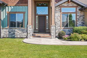Property entrance featuring stone siding and a lawn