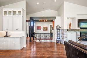 Kitchen with white cabinets, dark wood-style floors, vaulted ceiling, glass insert cabinets, and recessed lighting