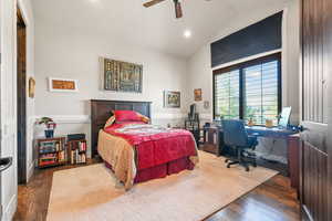 Bedroom with wood finished floors, a desk, a ceiling fan, and high vaulted ceiling