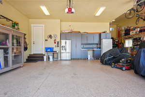 Garage featuring stainless steel fridge, freestanding refrigerator, and a garage door opener
