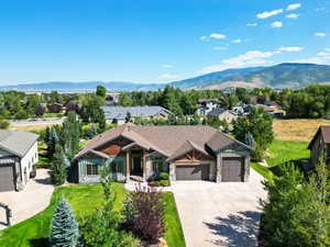 View of front of house with stone siding, an attached garage, a mountain view, and covered porch