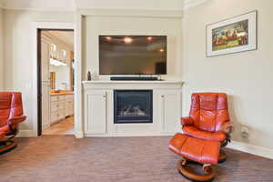 Living area with a glass covered fireplace, light carpet, and crown molding