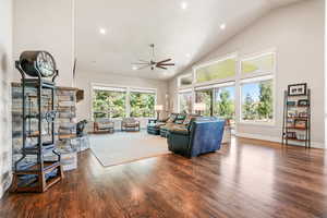 Living area with recessed lighting, dark wood-type flooring, high vaulted ceiling, a ceiling fan, and a fireplace
