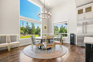 Dining space with a high ceiling, dark wood finished floors, and a chandelier