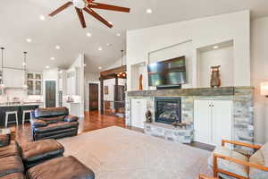 Living area with dark wood finished floors, a fireplace, a ceiling fan, recessed lighting, and high vaulted ceiling