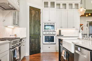 Kitchen with glass insert cabinets, white cabinets, and stainless steel appliances