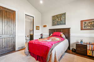 Bedroom with wood finished floors, vaulted ceiling, ensuite bathroom, and crown molding
