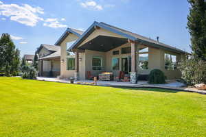 Rear view of property featuring stucco siding, a lawn, a patio area, and an outdoor fire pit