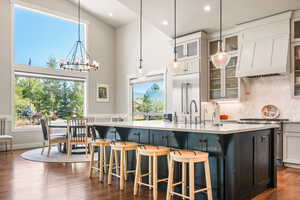 Kitchen with tasteful backsplash, white cabinets, glass insert cabinets, a kitchen bar, and a high ceiling