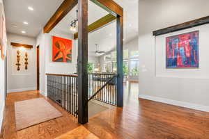 Corridor with an upstairs landing, beamed ceiling, wood finished floors, recessed lighting, and high vaulted ceiling