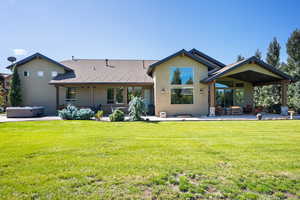 Back of house featuring stucco siding, a patio, a hot tub, and a yard