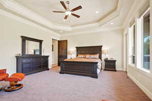Bedroom featuring a tray ceiling, light colored carpet, recessed lighting, ornamental molding, and ceiling fan
