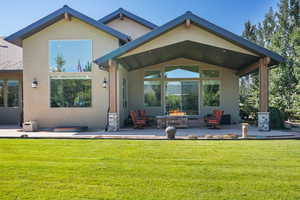 Rear view of house featuring a patio area, an outdoor fire pit, stucco siding, and a lawn
