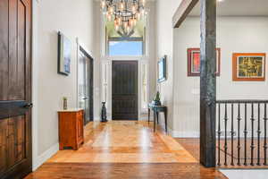 Foyer entrance featuring a high ceiling, a chandelier, light wood-type flooring, and inlaid floor details