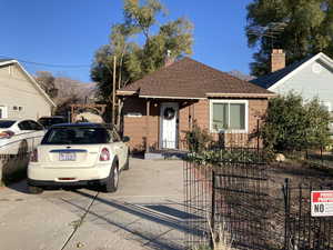 View of front of house with a shingled roof, a fenced front yard, and a chimney