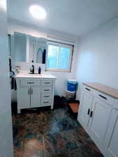 Full bathroom featuring stone finish flooring and vanity