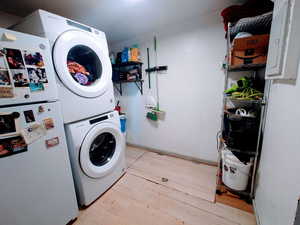 Laundry area with light wood-type flooring and estacked washer and dryer