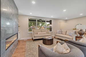 Living room featuring light wood-type flooring, recessed lighting, and a fireplace