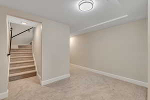 Finished basement with stairs and light colored carpet